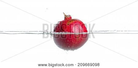 Red, green and ripe garnet falls into the water. Water splashes. Isolated picture on white background