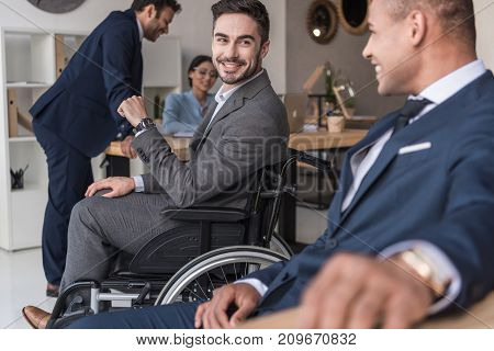 selective focus of smiling disabled businessman and colleagues in office
