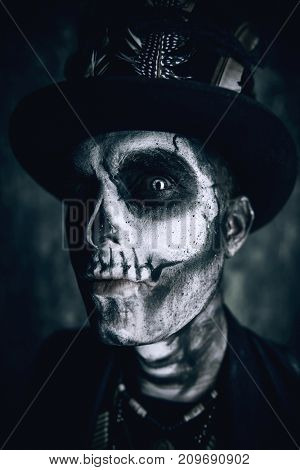 Close-up portrait of a man with a skull makeup dressed in a tail-coat and a top-hat. Baron Saturday. Baron Samedi. Dia de los muertos. Day of The Dead. Halloween.