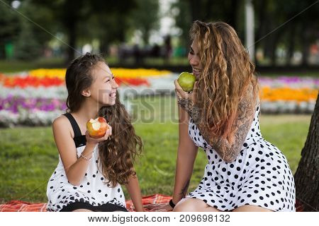 Healthy eating. Family lifesyle. Mother care for teenager, tasty fruit diet, nature background. Happy leisure time outdoors, stylish and pretty females together