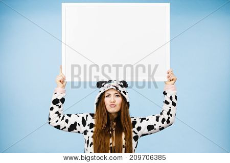 Positive teenage girl in funny nightclothes pajamas cartoon style with blank empty banner board. Advertisement copyspace.