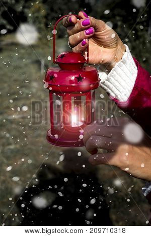 Woman hand with latern. Christmas background with snow in outdoor