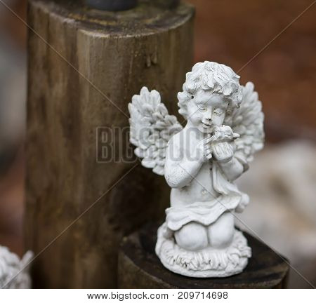 Stone Child Angel figurine sitting on wooden fence