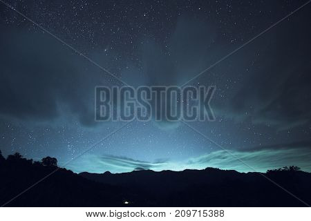 Long exposure and High ISO shot of star and cloud over the mountain at night. blue tone effect.