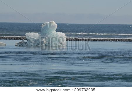 Stunning view of a unique iceberg with black sand in the background