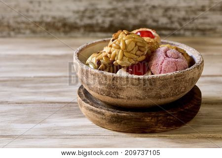 closeup of a rustic bowl with some panellets, typical confection eaten in All Saints Day in Catalonia, Spain, on a wooden table