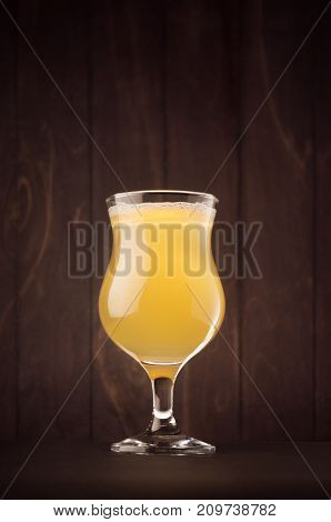 Tulip beer glass with muddy weizen on dark wood board vertical. Template for advertising design branding identity restaurant menu cover.