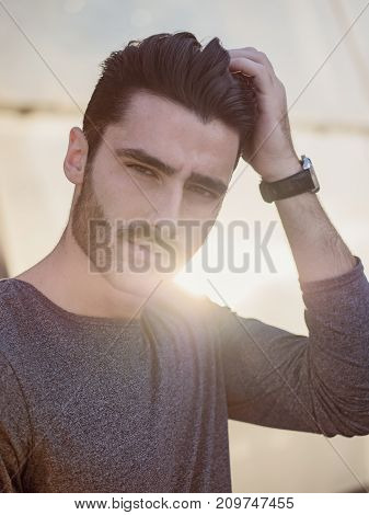 Attractive young bearded man portrait in urban setting, looking at camera