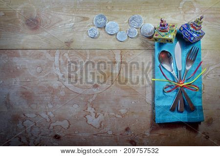 Casual Hanukkah dinner place setting with colorful napkin, dreidels, and gelt on old wood table