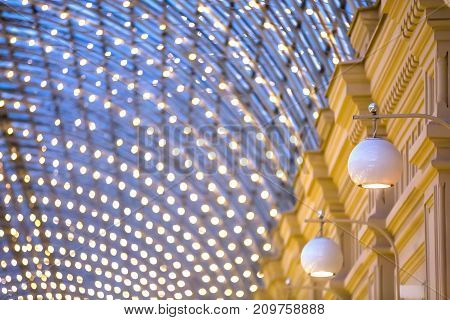 Designer glass white lamps hanging on the wall. Against the background of the roof of the shopping center. Copy space for text. Semicircular GUM roof, Moscow.
