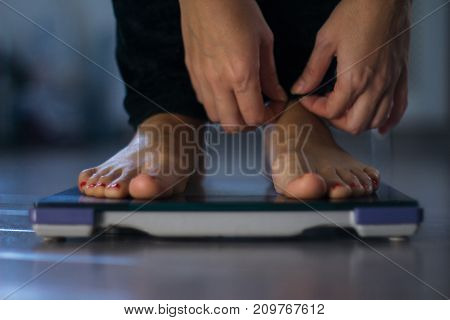 Female measuring weight on health scale close-up. Woman legs approaching to weighing digital instrument