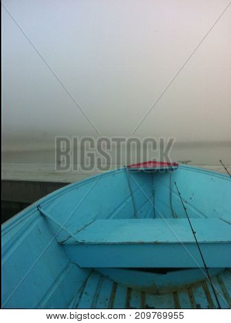 Blue boat heading into the fog, early morning