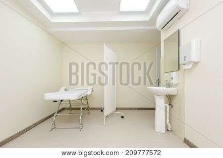 Clean designed and brightly lit massage room with empty table