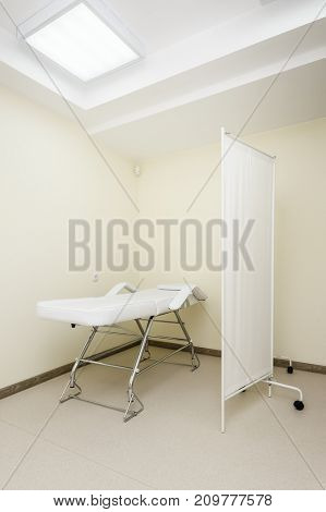 Clean designed and brightly lit massage room with empty table