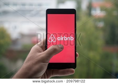 London, United Kingdom, october 3, 2017: Man holding smartphone with Airbnb logo with the finger on the screen