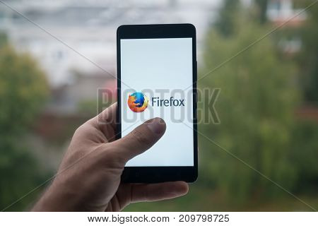 London, United Kingdom, october 3, 2017: Man holding smartphone with Mozilla firefox logo with the finger on the screen