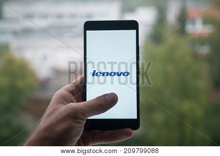 London, United Kingdom, october 3, 2017: Man holding smartphone with Lenovo logo with the finger on the screen