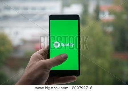 London, United Kingdom, october 3, 2017: Man holding smartphone with Spotify logo with the finger on the screen