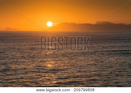A bright orange sunset over the mountains Dekelders near Gansbaai South Africa