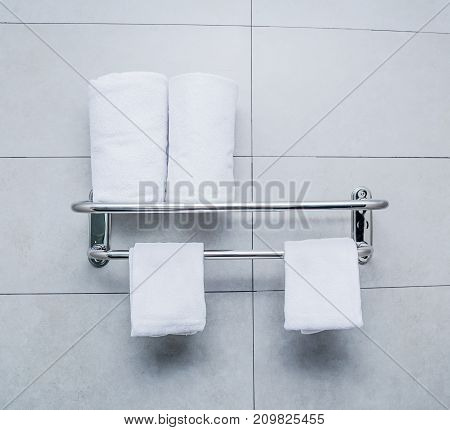 Stainless steel towel on grey cement wall with brown towel in bathroom