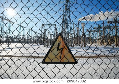 High-voltage transformer substation behind barbed-wire chain-link fence with Danger High Voltage sign.