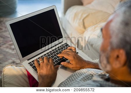 Senior man using laptop in the living room at home