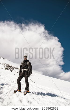 professional climbers go to the slope of Elbrus against the background of big storm cloud