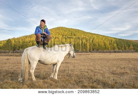 Mongolian Man Sitting On A Horse In A Fall Landscape Of Northern Mongolia