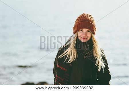 Young Woman smiling walking at winter sea Travel Fashion Lifestyle concept outdoor. Girl wearing orange hat and scarf cold weather