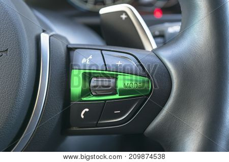 Hands free and media control buttons on the steering wheel in black leather modern car interior details