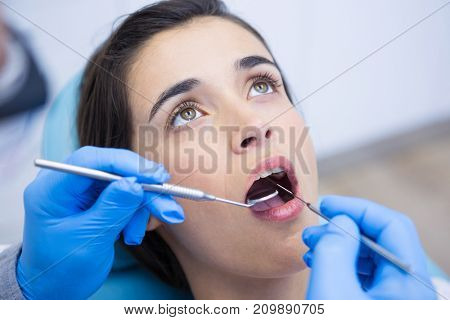 Close up of dentist holding equipments while examining woman at medical clinic