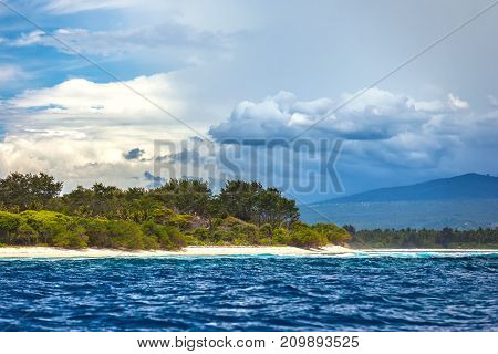 Variable weather above one island clouds and thunderclouds over another sunny beach. Meno Air Gili Trawangan island, Lombok, Indonesia.