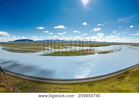 Travel to Iceland. road and river in a bright sunny mountain landscape. Vatna volcano covered with snow and ice on tne background.