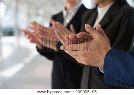 Three business people clap their hands to congratulate the signing of an agreement or contract between their firms companies enterprises. success dealing greeting and partner concept.