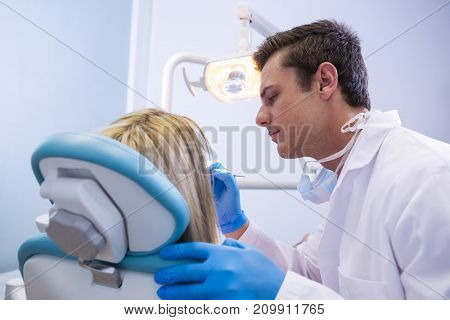 Side view of dentist polishing woman teeth at dental clinic