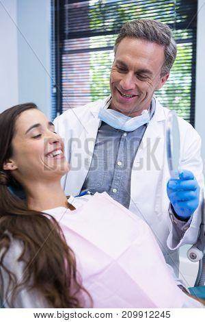Happy dentist showing mirror to patient at medical clinic