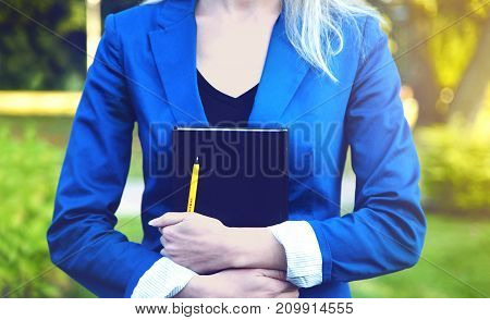 Book in hands of young student in park