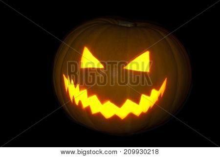 Classical pumpkin lantern brightly glowing from the inside on a black background