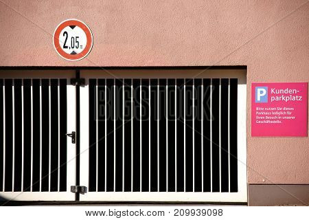 A closed iron gate in front of the parking lot of an underground car park with customer parking.