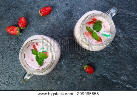 A top view on a two mason jar with jogurt and pieces of ice and green leaflets of mintson on a marble background. Close-up of drink. Food concept.