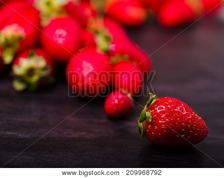 Fresh ripe fruits on a dark wooden table. Sweety red strawberries summer fruits on a dark brown background. Close-up of strawberry. Food concept.