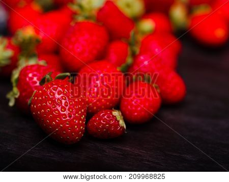 Fresh ripe fruits on a dark wooden table. Sweety red strawberries summer fruits on a dark brown background. Close-up of strawberry. Food concept.