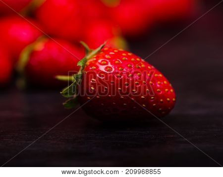 Fresh ripe fruits on a dark wooden table. Sweety red strawberries summer fruits on a dark brown background. Close-up of strawberry. Food concept.