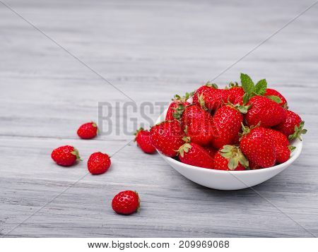 Fresh ripe fruits on a gray wooden table. Sweety red strawberries summer fruits on a gray background. Close-up of strawberry. Food concept.
