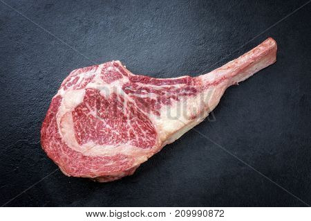 Raw dry aged wagyu tomahawk steak as close-up on black board 