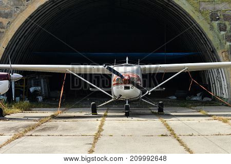 A small two-seater aircraft is in a hangar at the airport
