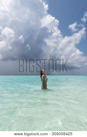 A Young Girl Makes Splashes When She Drastically Pulls Her Hair Out Of The Water.