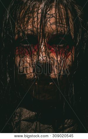 Spooky Infernal Girl With Black Eyes And Cracked Skin Close-up Portrait On Dark Background