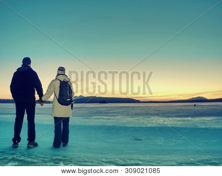 Traveler Stay On Ice Of Frozen Sea. Woman With Backpack And Long Warm Jacket. Footprints In Ice Of L