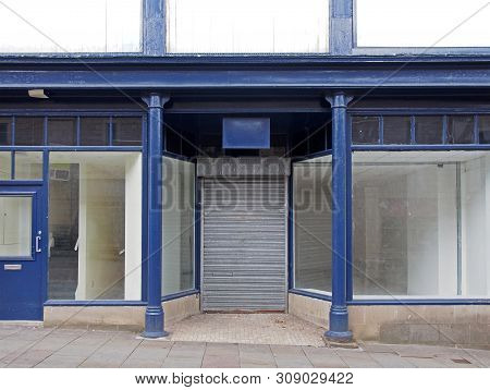 The Facade Of An Old Abandoned Shop Painted Blue And White With Empty Store Front Dirty Windows And 